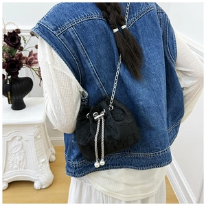 Detail view of floral embroidery and pearl drawstring on black satin bucket bag