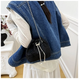 Detailed view of black jacquard bucket bag with silver chain and pearl drawstring charms