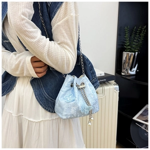 Detail of light blue lace bucket bag featuring butterfly embroidery and pearl charms