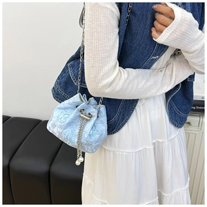 Detail of light blue jacquard bucket bag with floral texture, drawstring and pearl chain