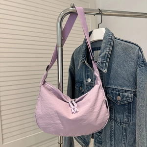 Detail van lichtpaarse nylon halve maantas met verstelbare riem aan een hanger