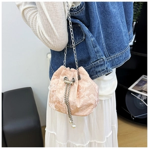 Detail showing pink jacquard drawstring bucket bag with floral pattern and pearl charms