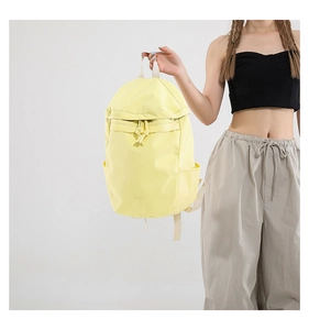 Detalle de mochila de nailon amarillo claro con correas blancas y bolsillos laterales