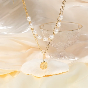 Double-layered gold paperclip chain and pearl necklace with hammered coin pendant