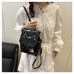 Détail d'un mini sac à dos noir brillant avec motif chat et fermeture à cordon