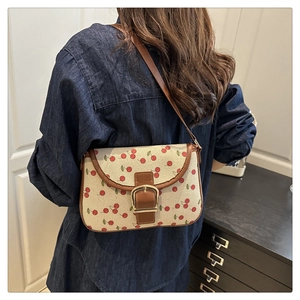 Détail du sac sous le bras en toile à motif cerises avec bandoulière en cuir sur modèle