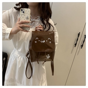 Détail d'un mini sac à dos en cuir verni marron foncé avec motif chat mignon et cordon serrage