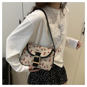 Détail du sac en toile à imprimé cerises avec boucle dorée et bordure en cuir noir