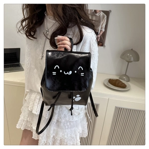 Détail d'un mini sac à dos noir en cuir avec un chat blanc mignon et empreinte de patte