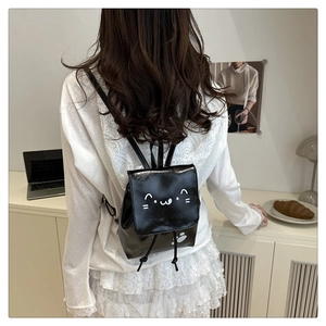 Detailed back view of a black mini bow backpack with cat print on a female model