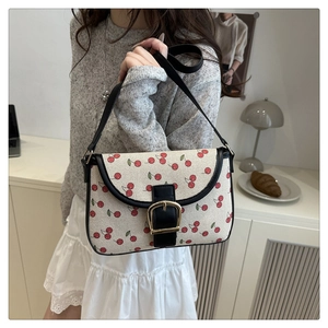 Mannequin portant un sac bandoulière en toile crème avec imprimé cerise et bordure cuir