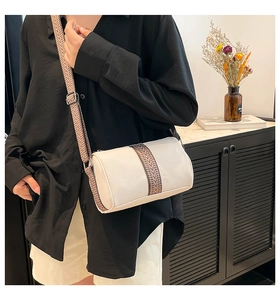 Detail of a creamy white cylindrical crossbody bag with ethnic jacquard woven strap