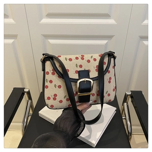 Détail du sac en toile imprimé cerises avec cuir noir et boucle dorée chic