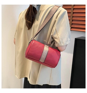 Detailed side view of red lychee leather barrel bag with bohemian geometric strap
