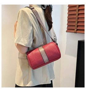 Detail of burgundy leather barrel bag with wide geometric patterned shoulder strap