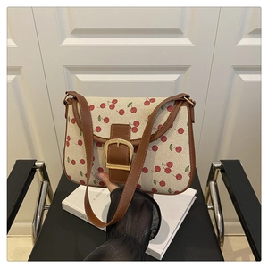 Détail du sac rétro avec imprimé cerises, bordure en cuir brun et boucle dorée