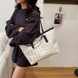 White textured tote bag with black bows and shoulder straps for stylish commuting