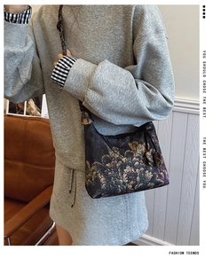 Detail of floral Xiangyun silk crescent bag showing vintage texture and shoulder strap