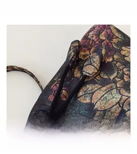 Macro view of vintage floral print handbag showing zipper closure and black drawstring ties