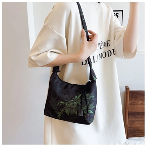 Detail of black silk shoulder bag featuring green leaf prints and textured finish