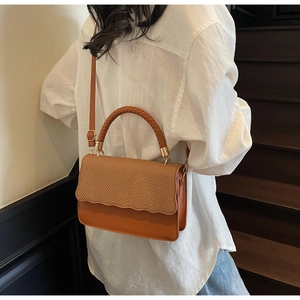 Sac à bandoulière marron avec rabat tressé et poignée texturée porté par un mannequin