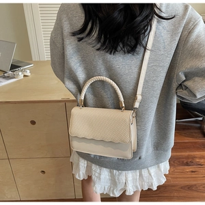Detail of cream shell bag featuring woven texture and decorative wavy edge finish