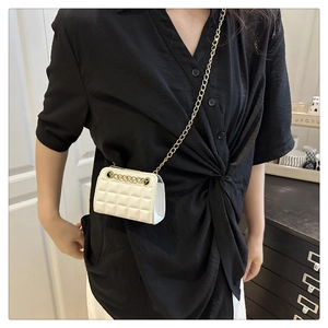Detailed view of white quilted mini bag with gold chain strap on a model shoulder