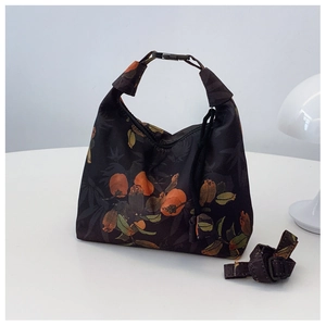 Detail of floral moon bag showing orange fruit print and adjustable strap on desk