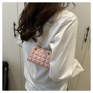 Detail of pink quilted mini crossbody bag with golden chain strap on a model shoulder