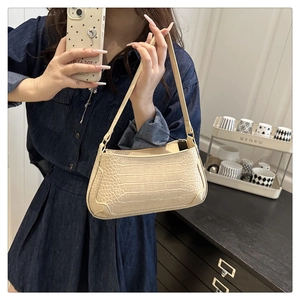 Detail of beige baguette bag with faux crocodile leather texture and sleek strap