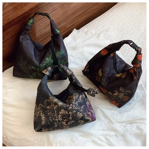 Three small patterned nylon tote bags with drawstring knots on a white surface