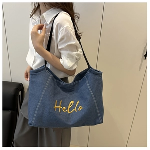 Detail of yellow Hello embroidery and contrast stitching on navy denim tote bag