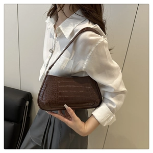 Close-up of a vintage dark brown baguette bag with crocodile pattern and leather strap