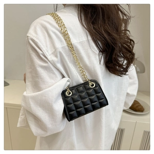 Detail shot of the black quilted chain crossbody bag featuring gold metal straps and texture