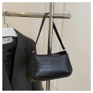 Detail of black crocodile texture PU leather baguette bag with shiny finish on silver rack