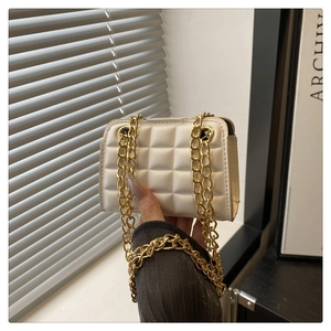 Detail of white quilted crossbody bag with golden chunky chain strap and square pattern