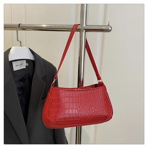 Detail of red crocodile pattern shoulder bag hanging on a minimalist silver metal rack