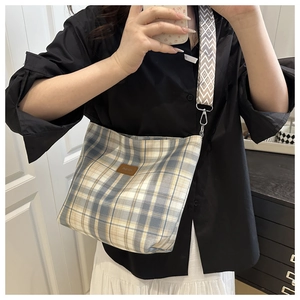 Detail of checkered canvas tote bag with adjustable wide strap and leather fashion logo patch
