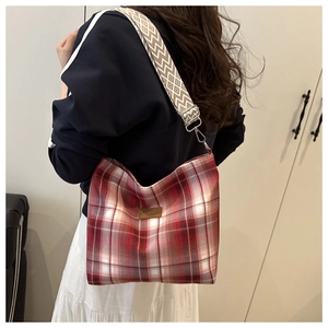 Detail of red checkered tote bag with wide geometric strap and leather logo patch