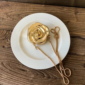Elegant gold rose shaped evening box bag with metal chain strap on vintage wood table