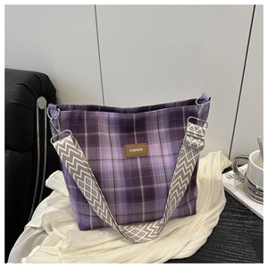 Detail of purple plaid tote bag with FASHION leather tag and geometric jacquard strap