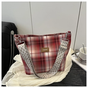Close-up of red and white checkered tote bag with a brown leather label and pattern strap