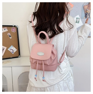 Detail of pink mini backpack featuring drawstring closure and silver brand metal plate
