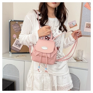 Close-up of pink mini backpack with drawstring closure and metal logo plaque on flap