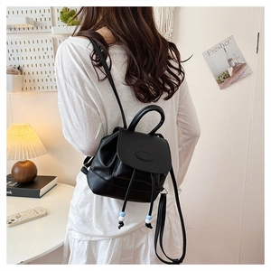 Detail shot of a black PU leather mini backpack showing the drawstring and bead detail