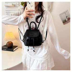 Close-up of a black mini PU leather backpack with drawstring closure worn by a model