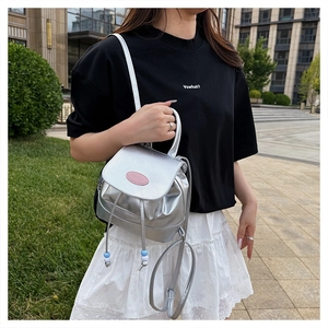 Detail of silver metallic backpack with pink brand label and colorful drawstring beads