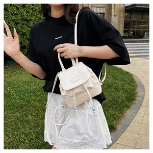 Close-up of minimalist cream white faux leather backpack with drawstring and logo