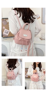 Detail of pink leather mini backpack featuring drawstrings and polished metal logo plate