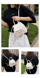 Detail of cream mini bucket backpack featuring drawstring closure and flap design